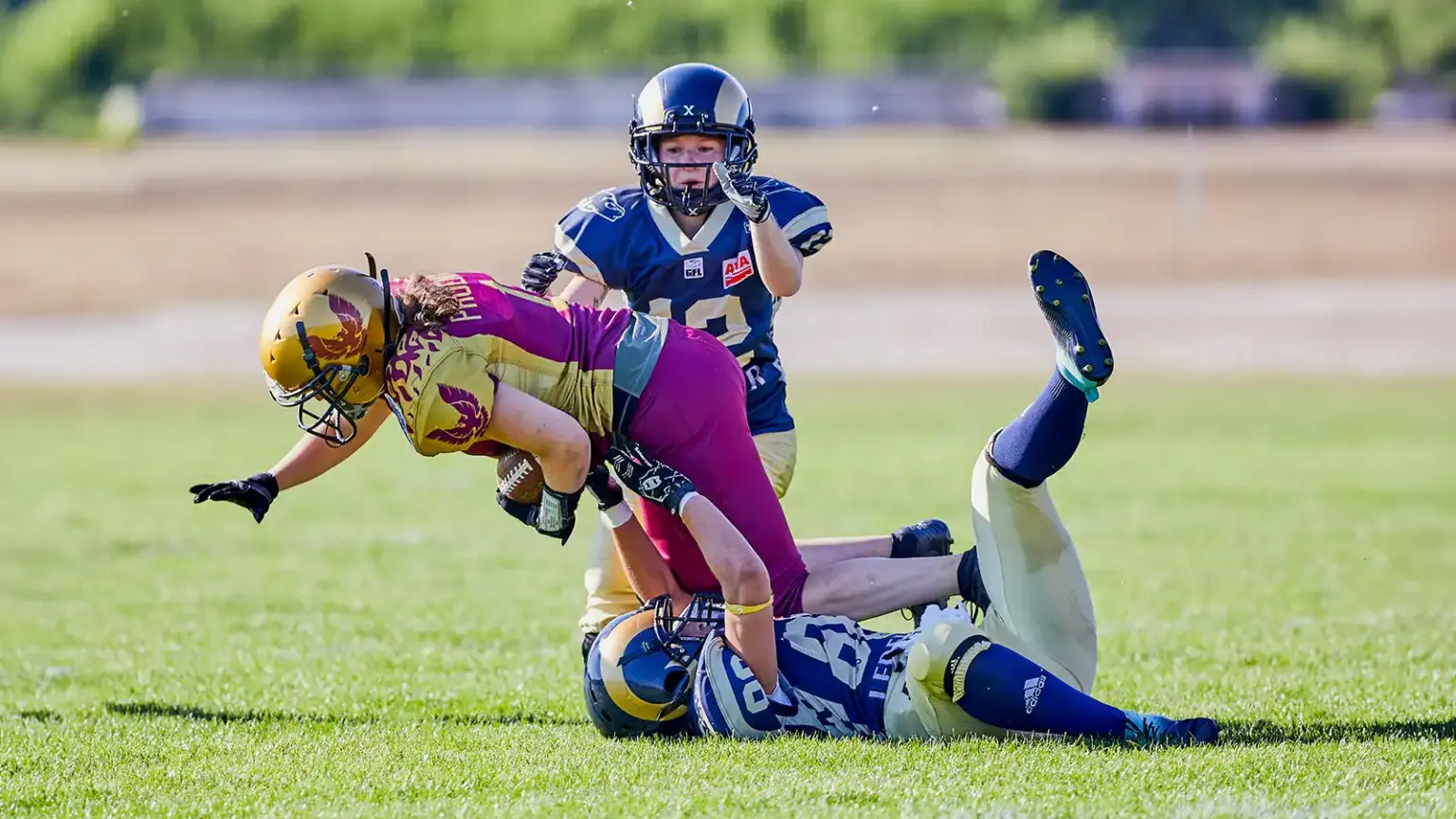 Spielerin im Frauen-American-Football wird nach einem Laufspiel getackelt