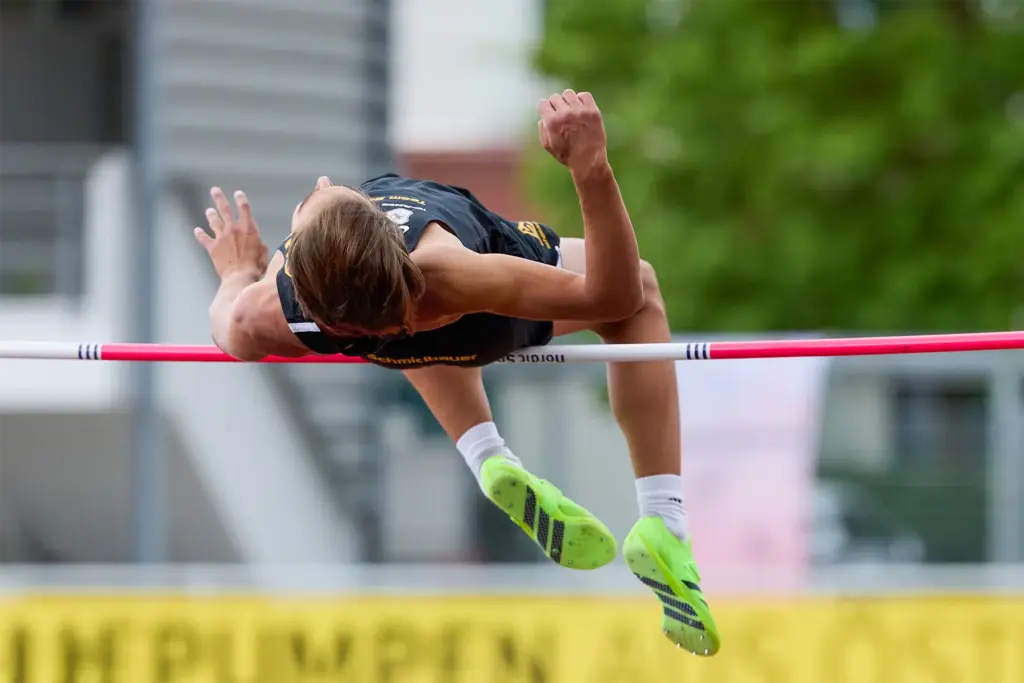 Hochspringer in der Flugphase über der Latte bei einem Leichtathletik-Wettkampf