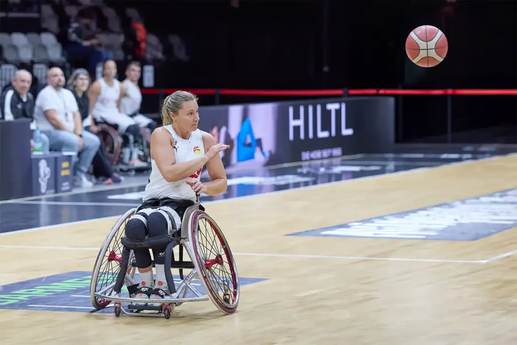 Rollstuhlbasketballspielerin spielt den Ball während eines RBBL2-Spiels über das Feld
