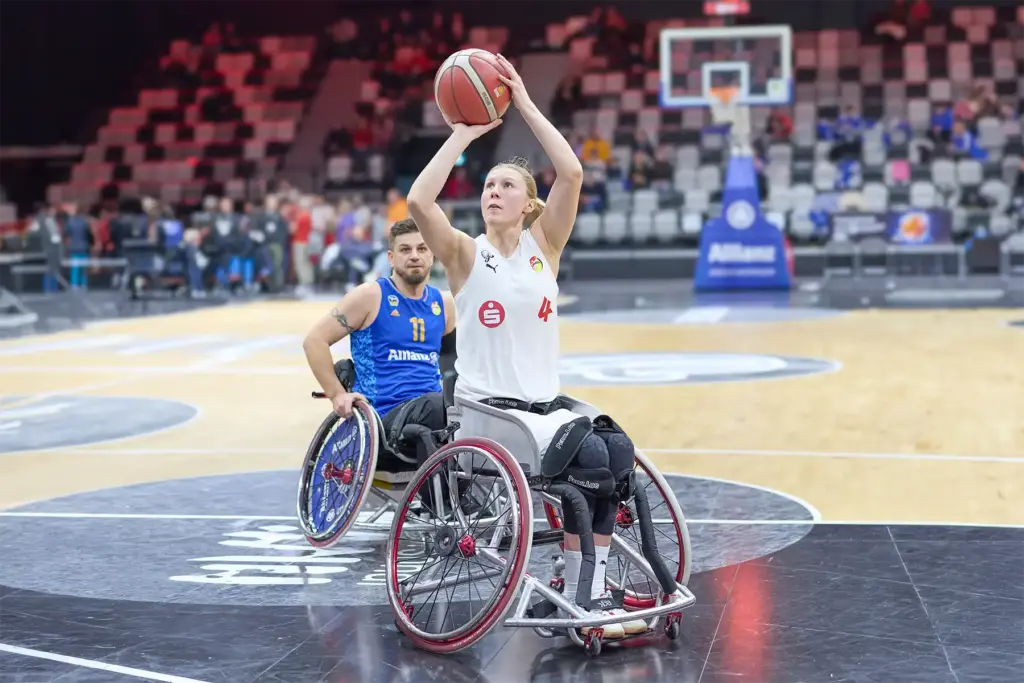 Rollstuhlbasketballspielerin setzt in einer Spielsituation unter dem Korb zum Wurf an
