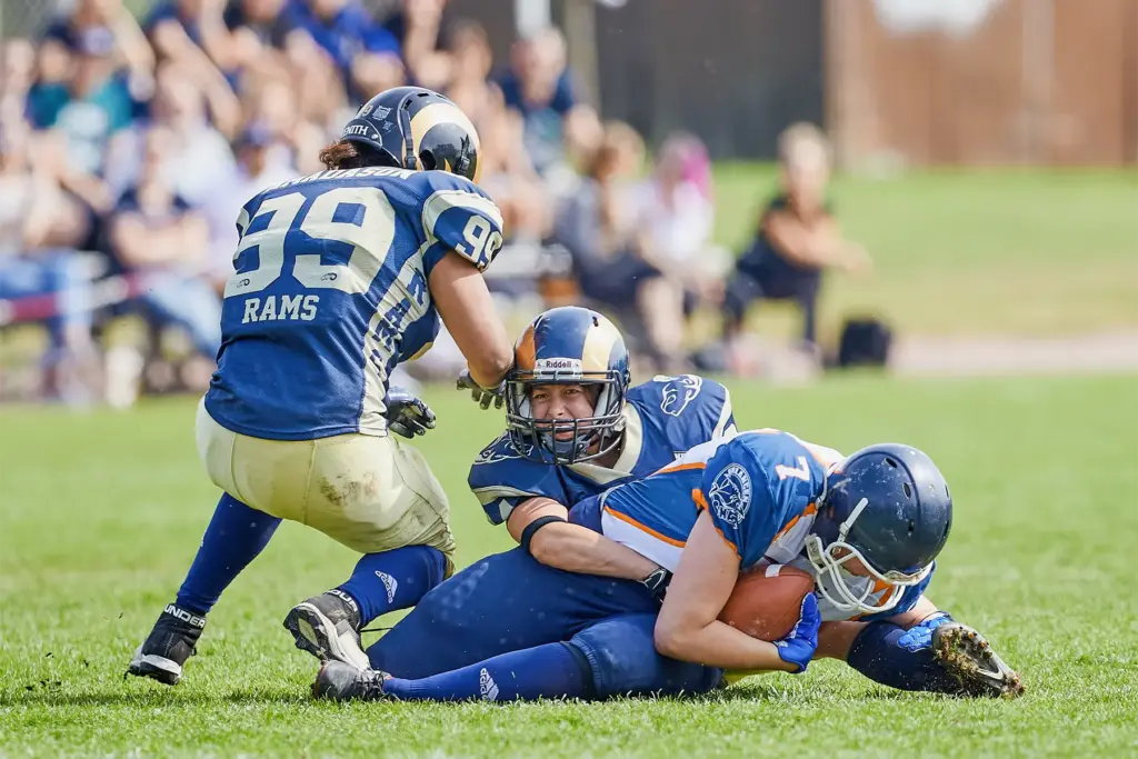 Eine Spielerin der Erlangen Sharks Ladies hält den Football fest, während Spielerinnen der Nürnberg Rams Ladies sie zu Boden bringen.