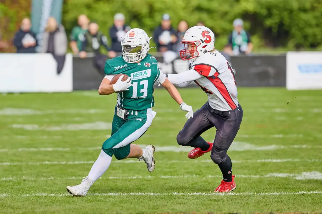 Eine Spielerin der Schwäbisch Hall Unicorns Women trägt den Football und sprintet über das Feld, während eine Spielerin der Scorpions Sisters sie verfolgt.