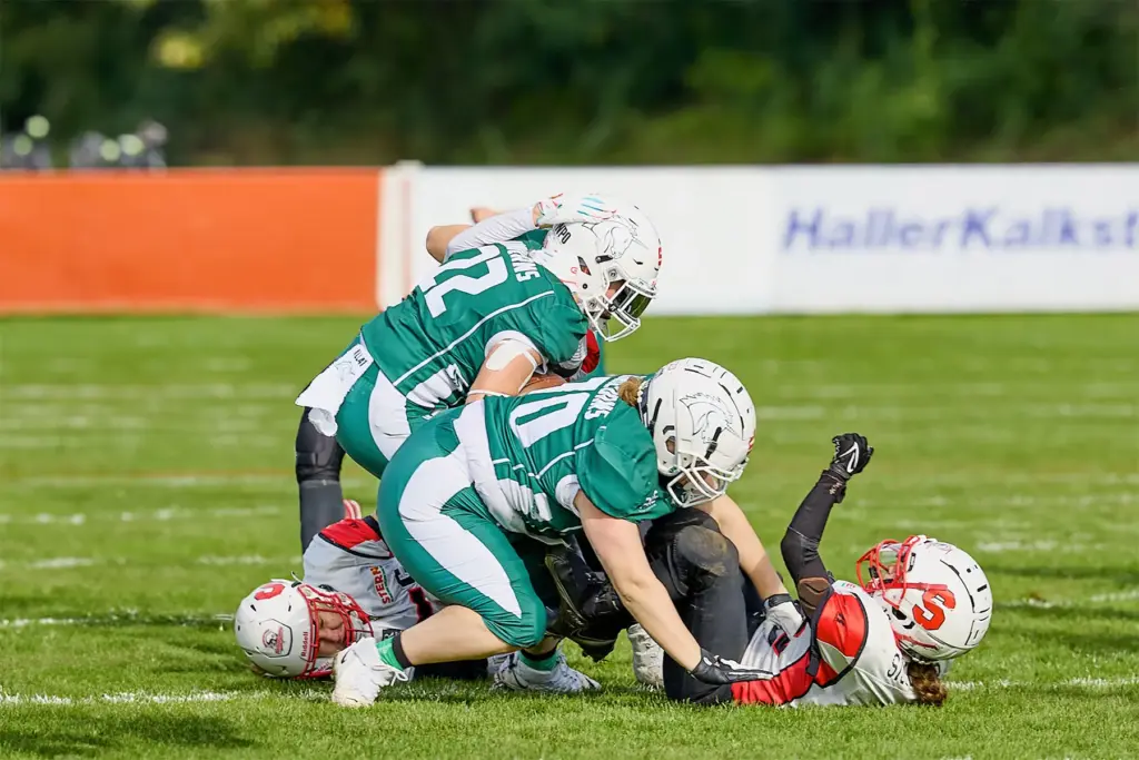 Mehrere Spielerinnen der Schwäbisch Hall Unicorns Women bringen eine Spielerin der Scorpions Sisters bei einem intensiven Tackle zu Boden.