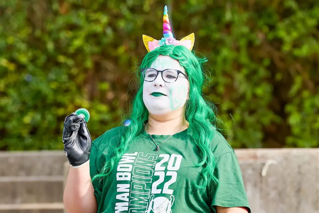 Ein Fan der Schwäbisch Hall Unicorns mit grüner Perücke, Einhorn-Haarreif und Gesichtsbemalung steht beim Ladiesbowl am Spielfeldrand.